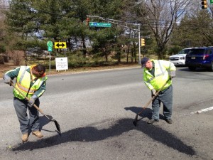 Marquettes Roach (left) and Richard Kosch (right) of the Public Works Department repair a large pothole today on Hope Road at the corner of Sycamore Avenue. In the background is one of the “See a Pothole?” signs.    