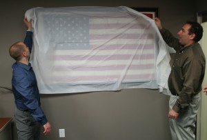 Michael Fabozzi and Matt  Dickens of the RAINE Foundation unveil the Leadership Flag at Sen Joe Kyrillos's legislative office. April 24, 2014