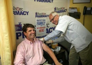 Scott Eagelton, co-owner of Bayshore Pharmacy, administers a flu shot to his partner, Richard Stryker